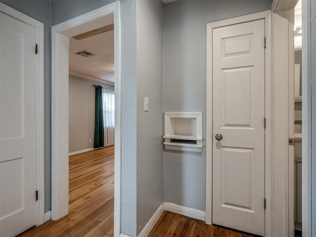 corridor with wood-type flooring and ornamental molding