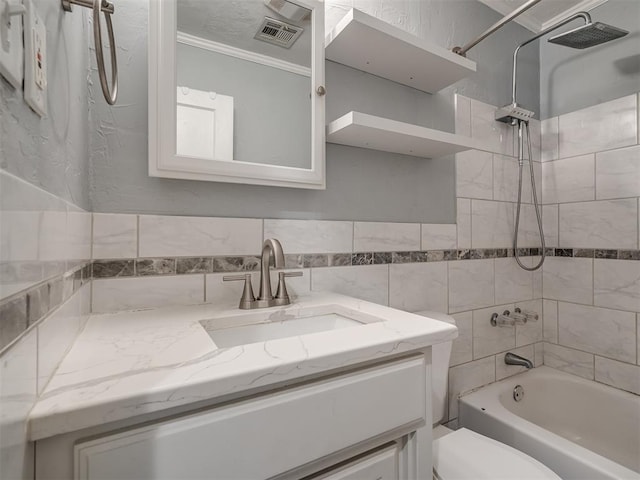 full bathroom featuring toilet, vanity, tiled shower / bath combo, and tile walls