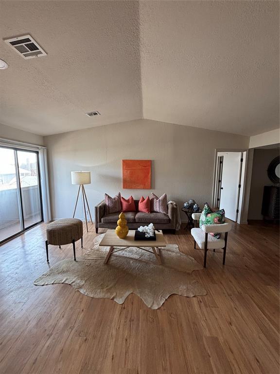 living room with hardwood / wood-style flooring, lofted ceiling, and a textured ceiling