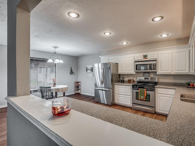 kitchen with stainless steel appliances, a chandelier, dark hardwood / wood-style floors, white cabinetry, and hanging light fixtures