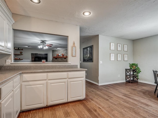 kitchen with kitchen peninsula, light hardwood / wood-style floors, white cabinetry, and ceiling fan