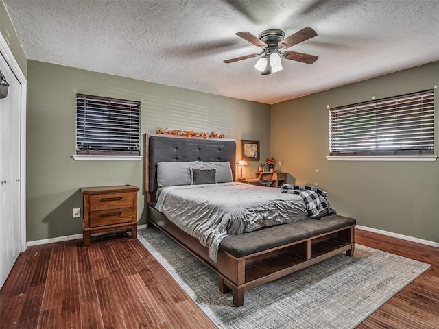 bedroom with a textured ceiling, a closet, dark hardwood / wood-style floors, and ceiling fan