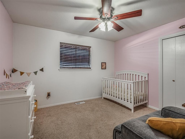 carpeted bedroom featuring ceiling fan, a closet, and a nursery area