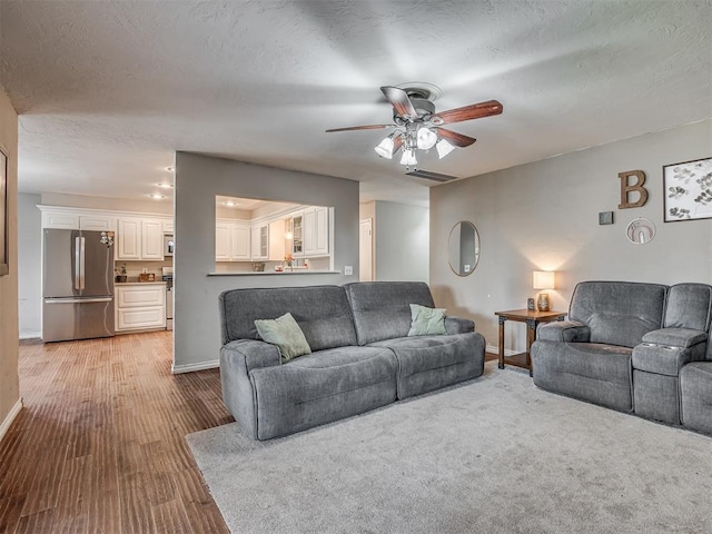 living room with ceiling fan and a textured ceiling