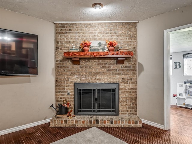 room details featuring wood-type flooring, a textured ceiling, and a brick fireplace