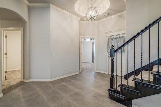 carpeted foyer entrance featuring an inviting chandelier and ornamental molding