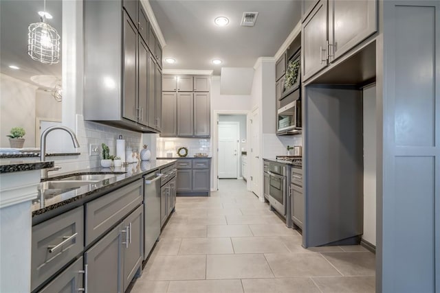 kitchen featuring sink, hanging light fixtures, dark stone counters, gray cabinets, and stainless steel appliances