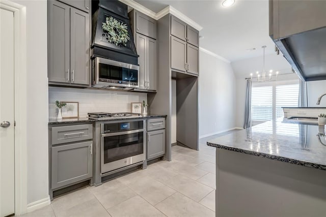 kitchen featuring pendant lighting, gray cabinets, tasteful backsplash, and appliances with stainless steel finishes