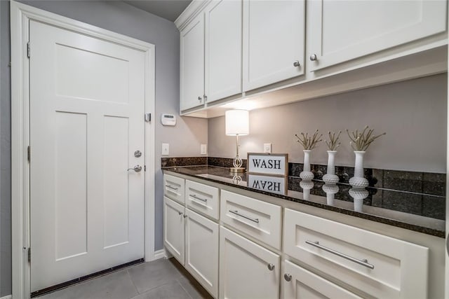 kitchen with white cabinetry, dark stone counters, and light tile patterned flooring