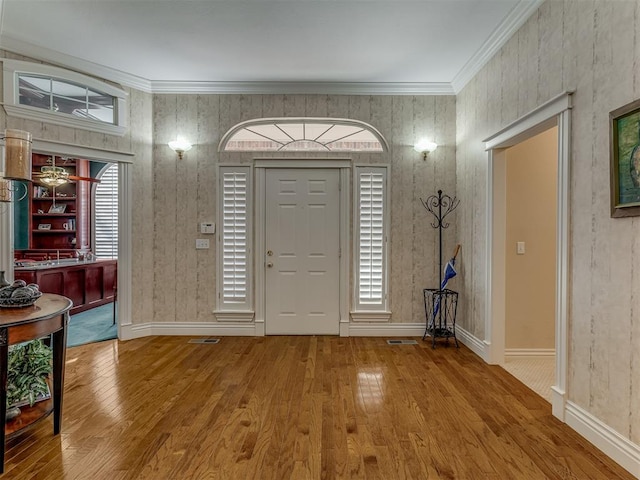 entrance foyer with ornamental molding, hardwood / wood-style floors, and a wealth of natural light