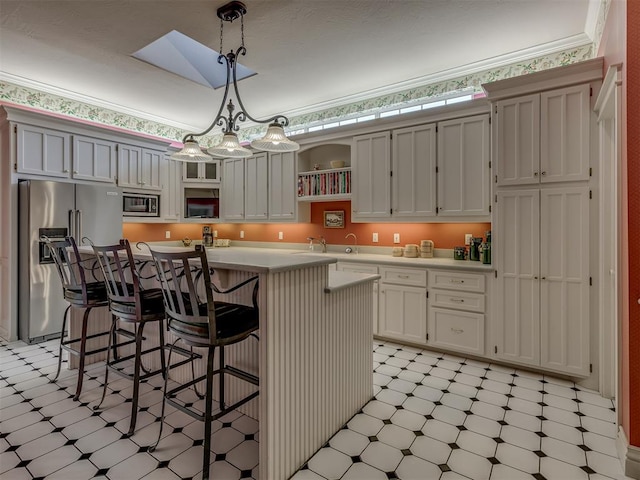 kitchen featuring a breakfast bar, hanging light fixtures, stainless steel appliances, white cabinets, and a center island with sink