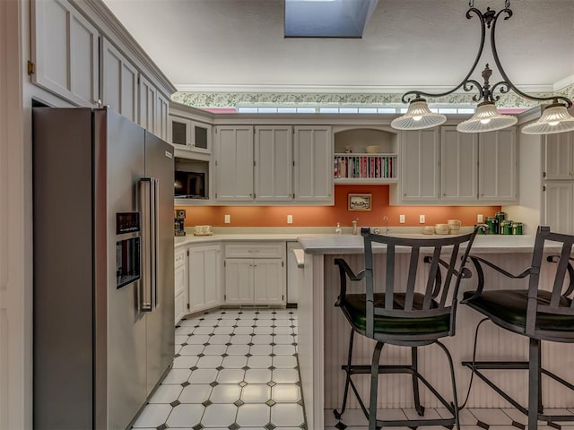 kitchen featuring hanging light fixtures, white cabinetry, high end fridge, and a kitchen breakfast bar