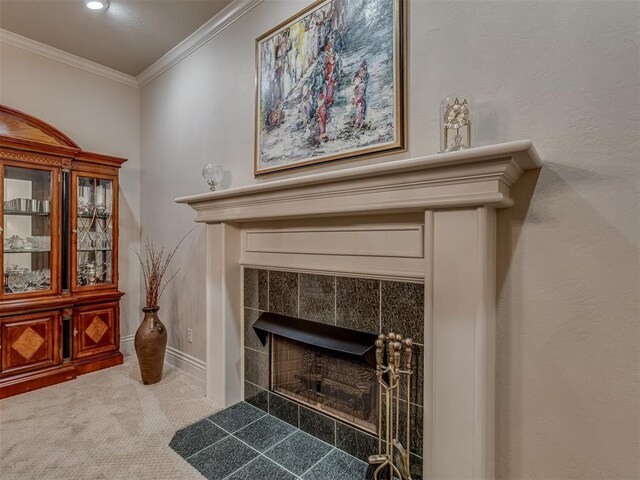 interior details featuring a tiled fireplace, ornamental molding, and carpet flooring