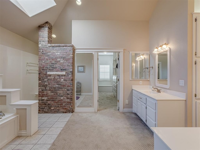 bathroom with tile patterned flooring, a skylight, high vaulted ceiling, vanity, and a bathing tub