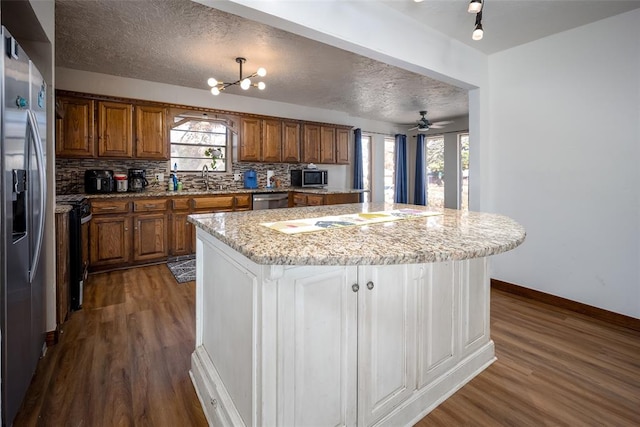 kitchen with a textured ceiling, a center island, and stainless steel appliances