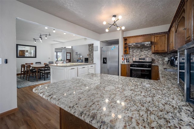 kitchen with kitchen peninsula, dark hardwood / wood-style flooring, a textured ceiling, and appliances with stainless steel finishes