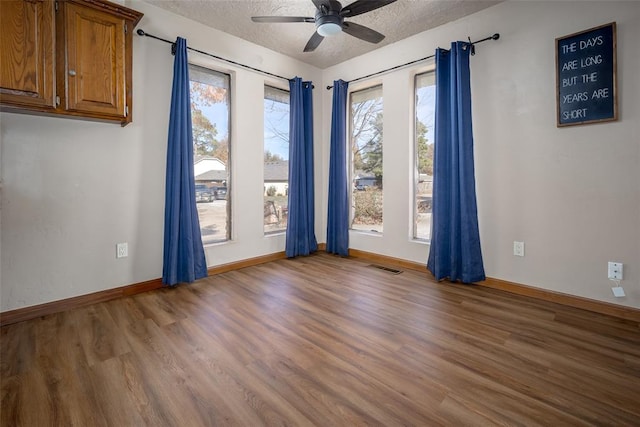 spare room with hardwood / wood-style floors, plenty of natural light, and a textured ceiling