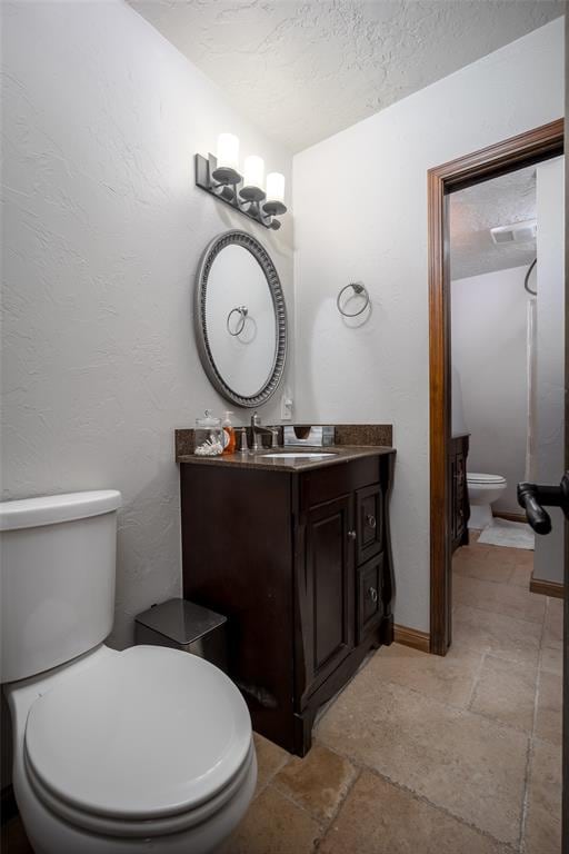 bathroom with vanity, toilet, and a textured ceiling