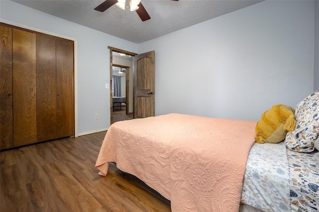 bedroom featuring a textured ceiling, a closet, ceiling fan, and dark wood-type flooring