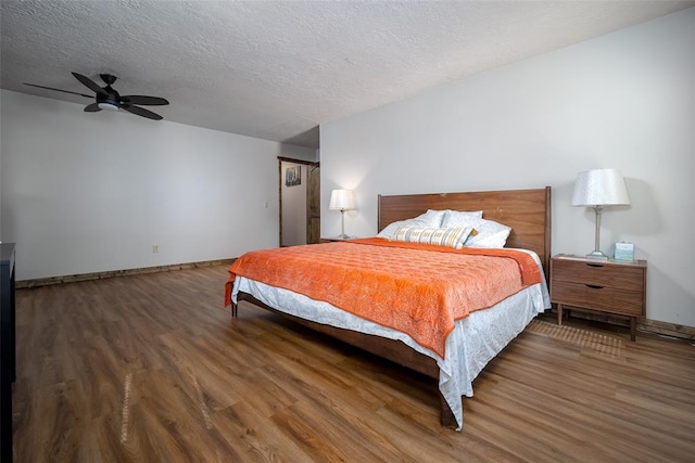 bedroom with a textured ceiling, dark hardwood / wood-style floors, and ceiling fan