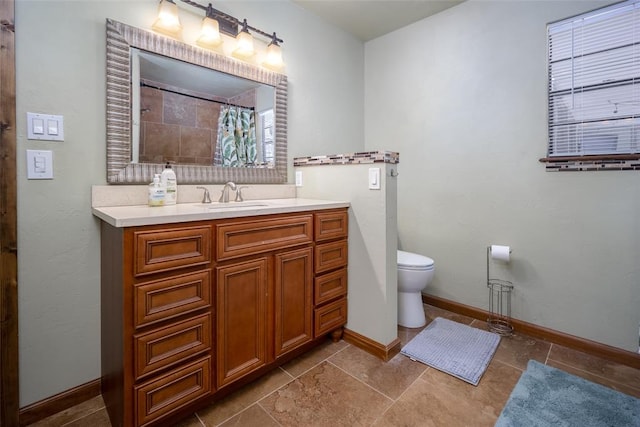 bathroom with walk in shower, vanity, and toilet