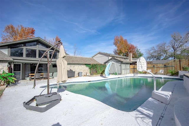 view of pool featuring a patio, a shed, and a water slide