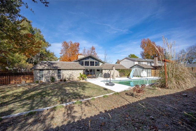 rear view of property with a fenced in pool, a storage unit, a patio area, and a lawn