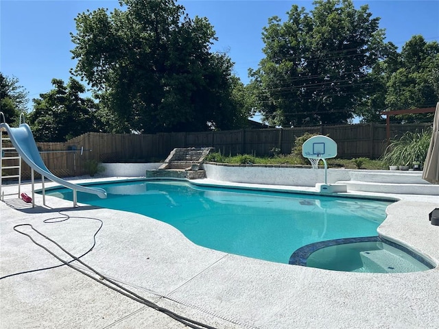 view of swimming pool featuring an in ground hot tub and a water slide