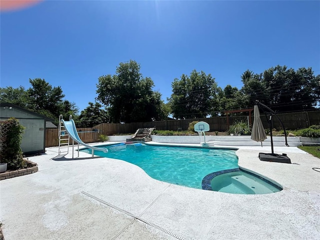 view of swimming pool with a patio, a shed, an in ground hot tub, and a water slide