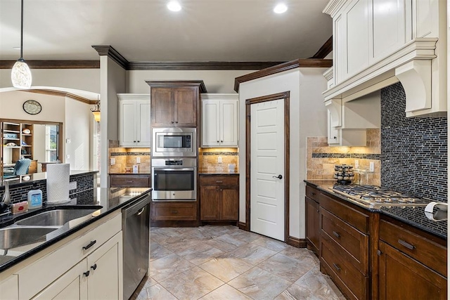 kitchen with pendant lighting, ornamental molding, appliances with stainless steel finishes, tasteful backsplash, and dark brown cabinets