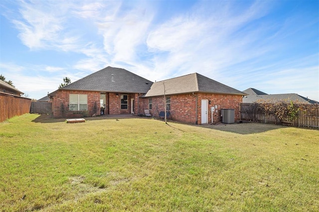 rear view of property with a lawn and central air condition unit