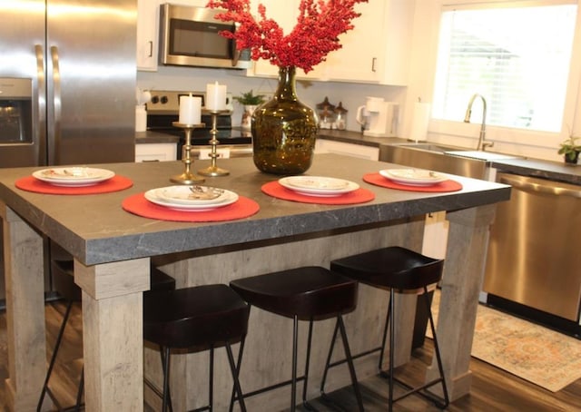 kitchen featuring a kitchen bar, dark hardwood / wood-style flooring, white cabinets, and appliances with stainless steel finishes