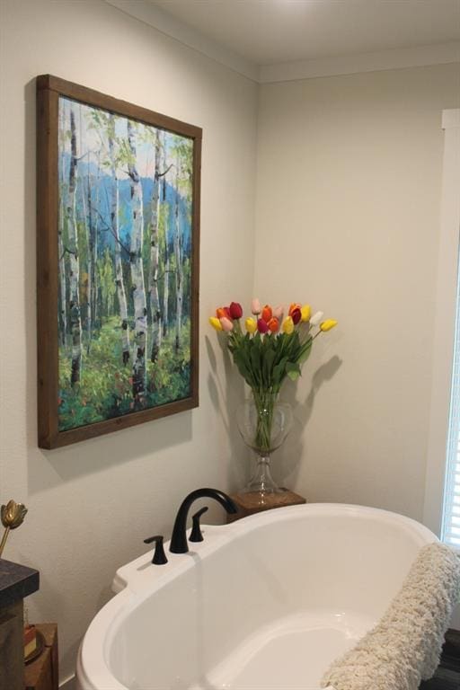 bathroom with crown molding, vanity, and a bath