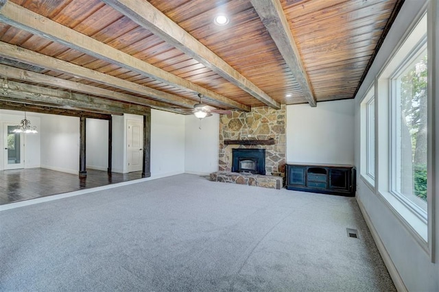 unfurnished living room featuring a wealth of natural light, beamed ceiling, wooden ceiling, and dark carpet