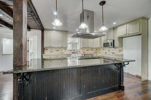 kitchen featuring pendant lighting, dark wood-type flooring, dark stone counters, decorative backsplash, and island range hood