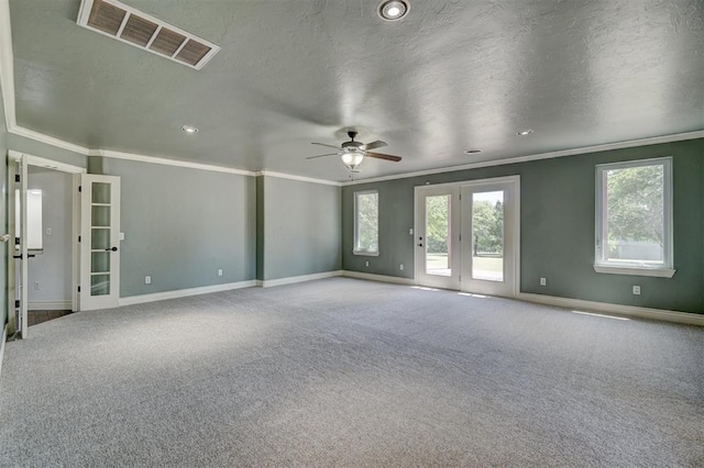 empty room with carpet flooring, ceiling fan, french doors, crown molding, and a textured ceiling