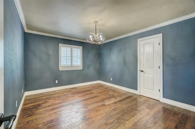 spare room with a notable chandelier, wood-type flooring, and ornamental molding