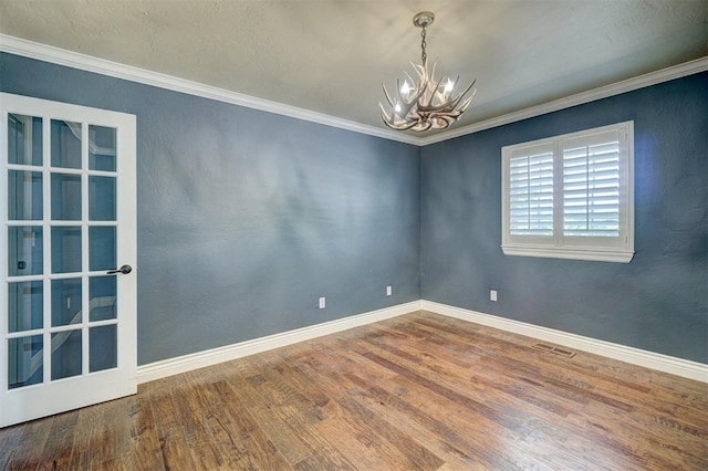 empty room with hardwood / wood-style floors, ornamental molding, and a chandelier