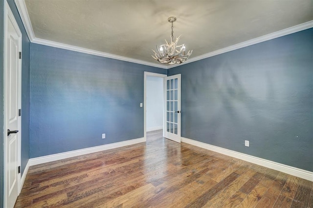 spare room with crown molding, wood-type flooring, and a notable chandelier