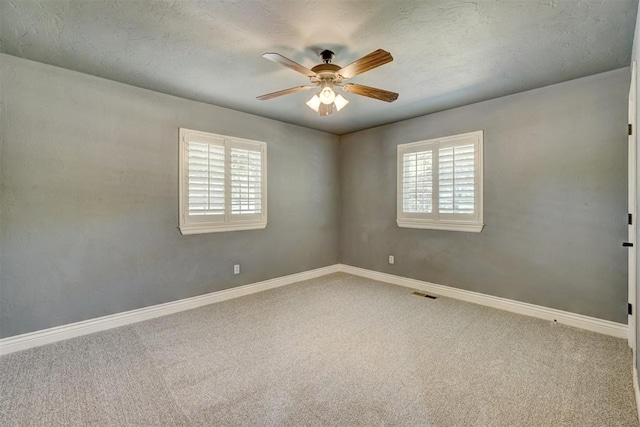 empty room with ceiling fan, carpet floors, and a textured ceiling