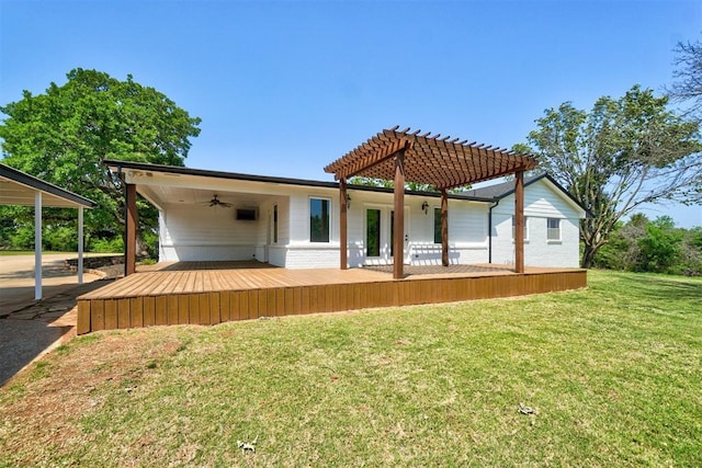 rear view of house with ceiling fan, a pergola, a wooden deck, and a lawn