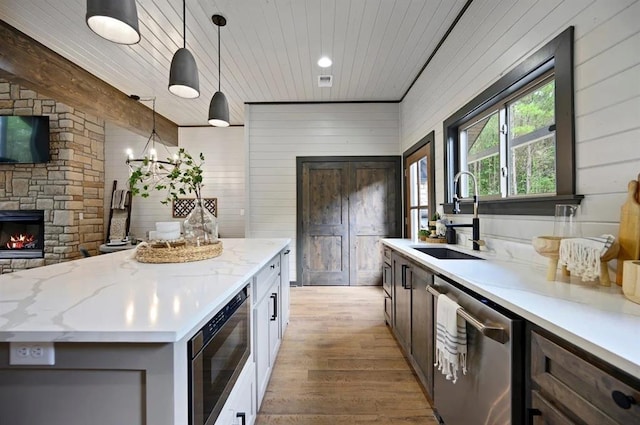 kitchen featuring light wood-type flooring, stainless steel appliances, sink, pendant lighting, and white cabinetry