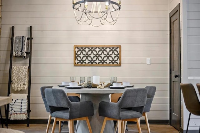 dining area featuring a chandelier, hardwood / wood-style flooring, and wooden walls