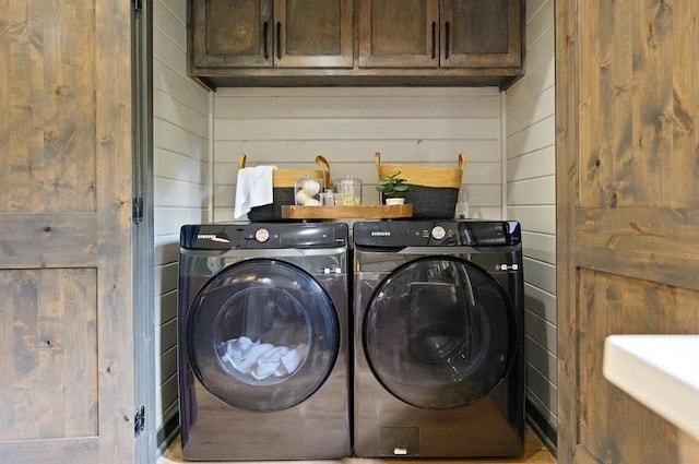 laundry area featuring cabinets, independent washer and dryer, and wooden walls