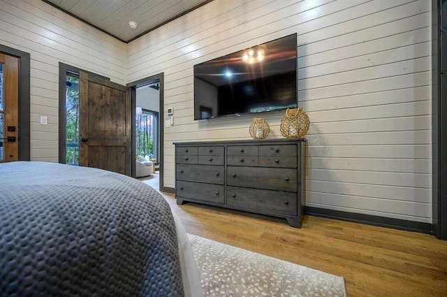 bedroom featuring wood walls and light hardwood / wood-style flooring