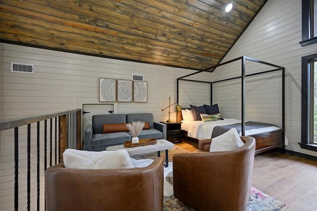 bedroom with wood walls, wood-type flooring, high vaulted ceiling, and multiple windows