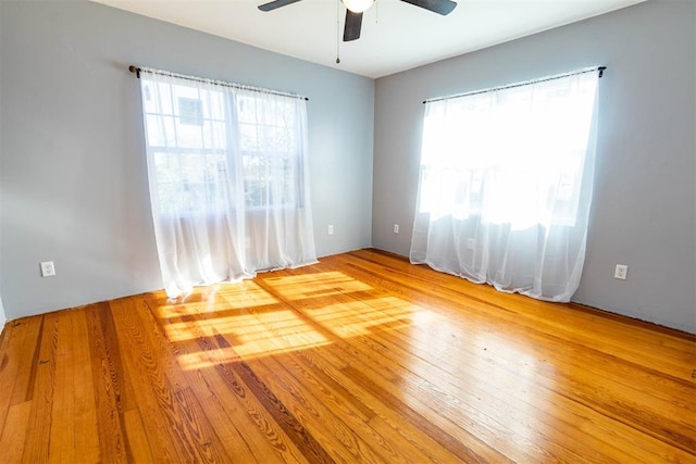 empty room featuring ceiling fan, hardwood / wood-style floors, and a healthy amount of sunlight