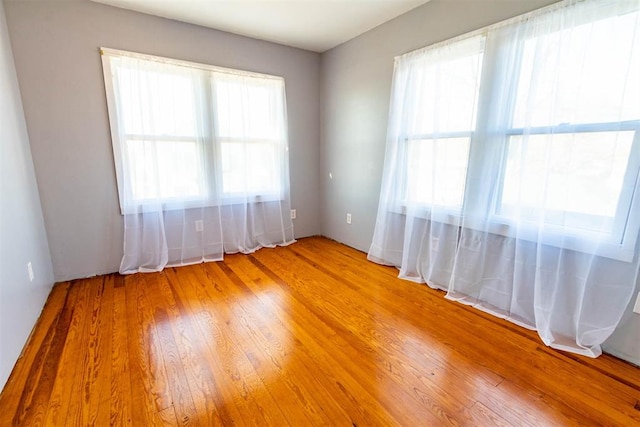 unfurnished room with hardwood / wood-style floors and a healthy amount of sunlight