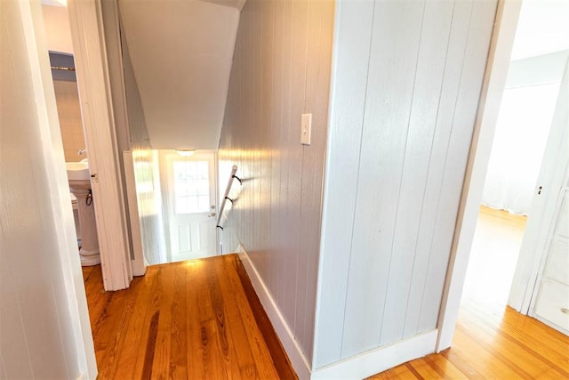 corridor with hardwood / wood-style floors and wooden walls