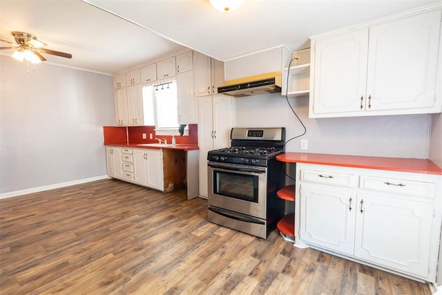 kitchen with exhaust hood, white cabinets, sink, stainless steel gas range, and hardwood / wood-style flooring